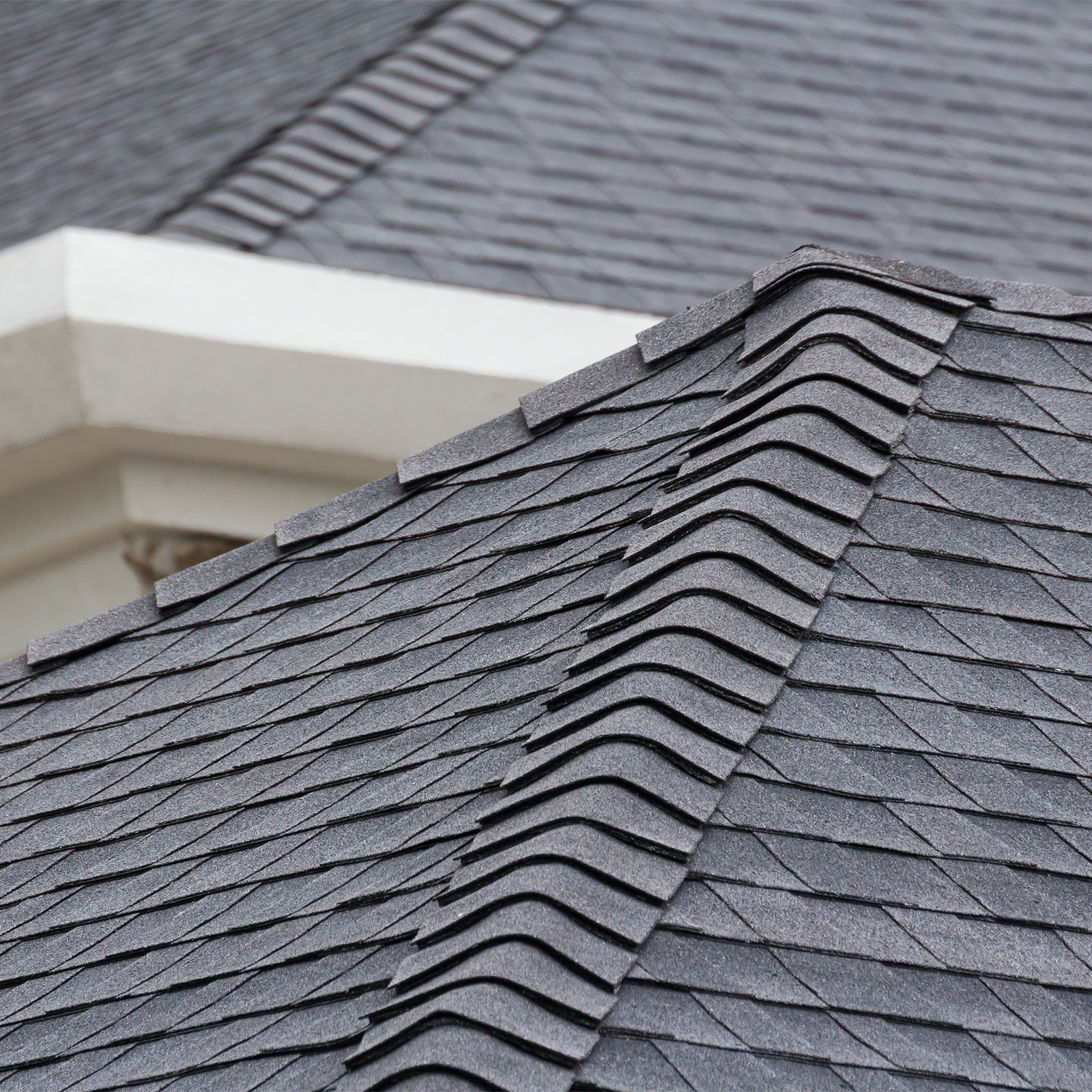 edge of Roof shingles on top of the house, dark asphalt tiles on the roof background. Bay
